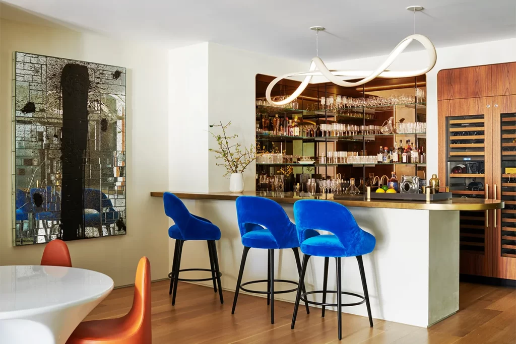 Chairs and a table by Ross Lovegrove define the dining area in the family room, while Lola bar chairs by Mambo Unlimited Ideas sit at the bar there. The chandelier above the counter is by John Procario.