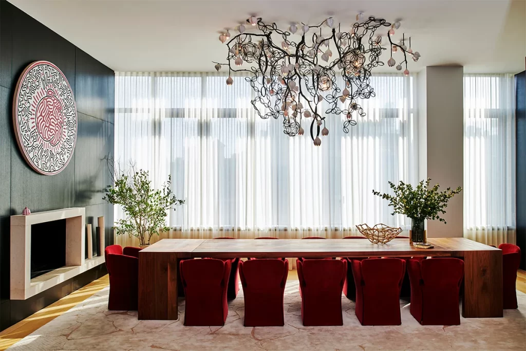A custom, site-specific chandelier by David Wiseman hangs over a monumental-size wood table surrounded by Moroso chairs in the formal dining room.