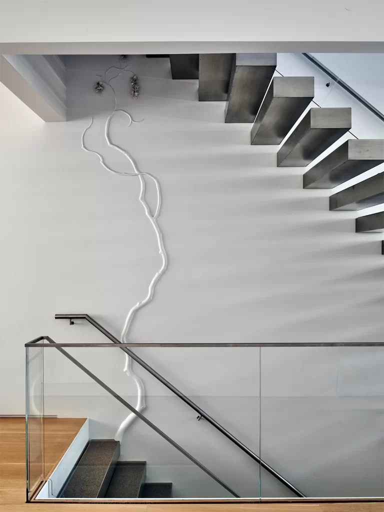 David Wiseman created a plaster bas-relief installation that climbs the home’s central staircase.